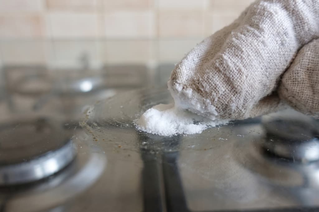Bicarbonate of soda paste lifting a baked-on mark from glass.